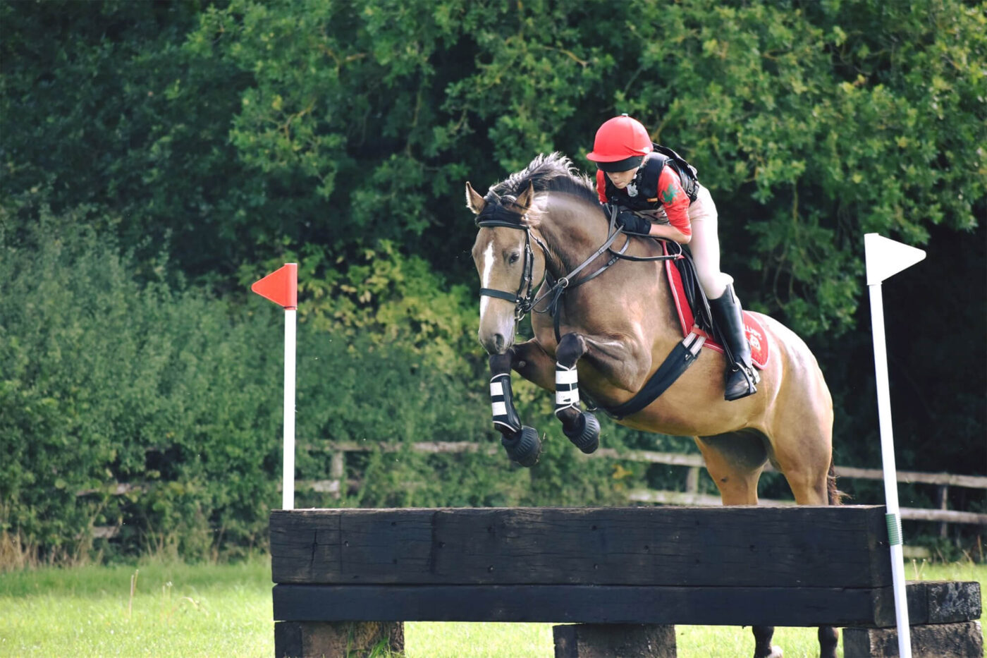 girl and pony jumping cross country fence