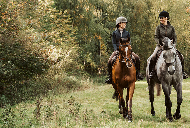 two horse riders in a field