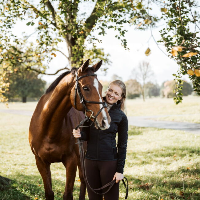 woman and horse standing underneath a tree
